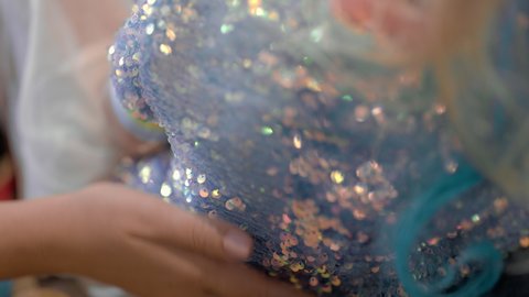 Mother stroking daughters dress with paillettes. Her child sparkling like a little princess