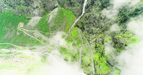 Cars climbing winding road in steep lush Trollstigen valley - aerial bird´s-eye
