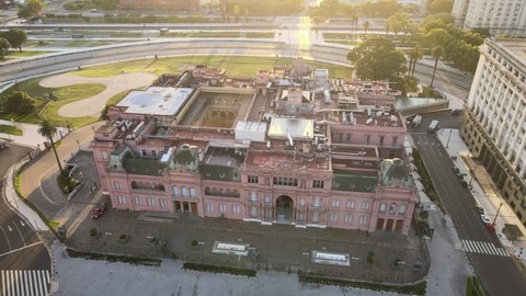 Aerial Drone Scene flying down Casa Rosada, Buenos Aires, Argentina, the presidential pink house. Warm dawn morning sun backlight of Historic building and flag. Flare, reflections.