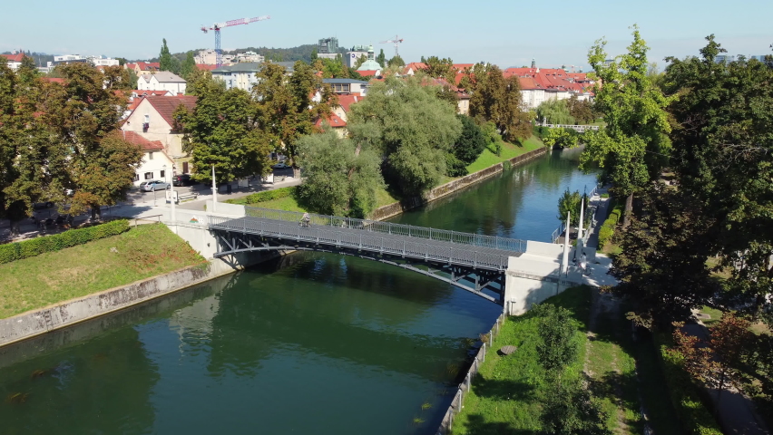 LJUBLJANA, SLOVENIA - CIRCA 2021: The Hradecky Bridge also known as the Hradeckega most, a cast iron arch bridge spans the Ljubljanica river in Trnovo district of Ljubljana. Aerial drone video.