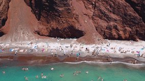 Aerial video of a drone camera on Santorini, Greece. Unique red beach on Santorini island made of volcanic rock of a former volcano
