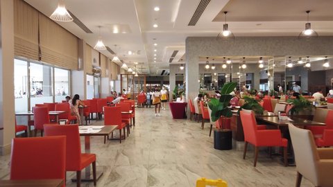 Turkey, Antalya, 20 August-2021. Resort hotel restaurant. Point of view of person who walks among tables with dining people. Masked waiters serve dishes and clean up leftover food.