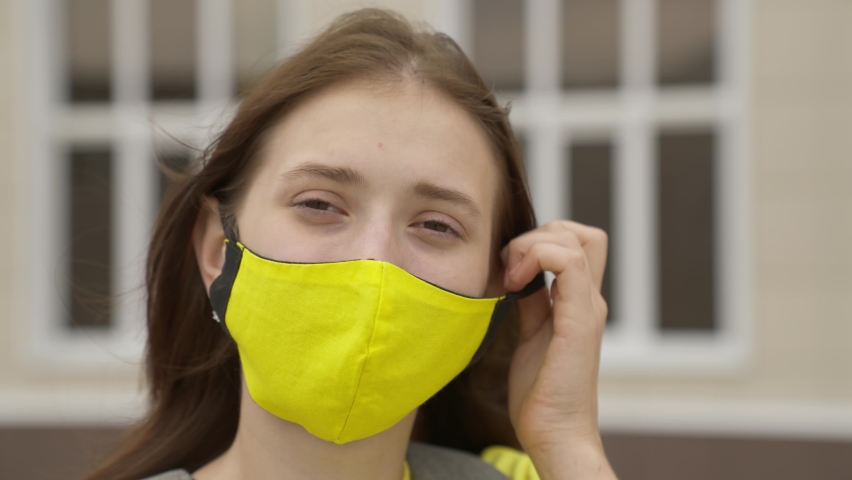 An adult schoolgirl puts on a face mask and smiles, pandemic 2022, filter air for the respiratory tract of the lungs, prevent COVID-19 infection, protect a person from coronavirus with a mask mode Royalty-Free Stock Footage #1079631305