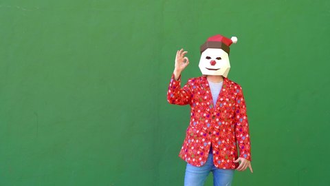 Anonymous person dressed in Christmas clothes and mask dancing animatedly.