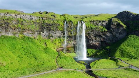 People Visit Seljalandsfoss Waterfall With Verdant Nature In Summer In South Iceland. - aerial