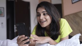 Young Asian Woman making a video call smiling and talking with her friend and family while laying on bed. Businesswoman having video call discussing, working online meeting with team at home.