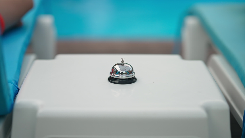 Hotel bell with little male and female hands pressing in slow motion outdoors. Unrecognizable brother and sister having fun sunbathing at swimming pool on summer resort