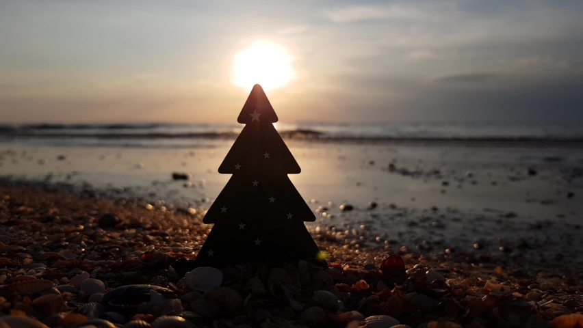 Christmas tree on the background of sea waves and sunset. Christmas on the beach. winter holidays in warm countries. New Year