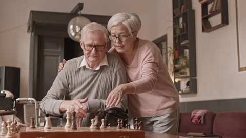 Slowmo shot of Caucasian senior couple spending leisure time playing chess game in nursing home