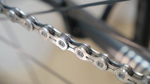 Rotating bicycle chain, close up. Bike gear. Bicycle workshop, maintenance and service. Mechanic repairing road bicycle