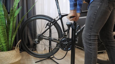Pumping up bicycle wheel. Bicycle mechanic pumps air into bike tire. Cyclist pumping bicycle wheel with foot pump. Bicycle repairing workshop