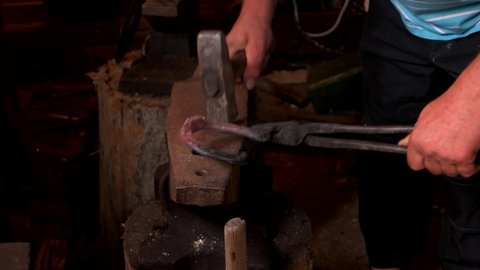 Forging a horseshoe on anvil with a hammer.