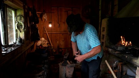 Blacksmith working with metal at forge.
