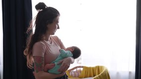 Mother and her Newborn Baby. Happy Mother holding her New born Baby girl kissing and hugging. Maternity concept. Parenthood. Motherhood. Beautiful Happy Family. Adoption. Slow motion 4K UHD video