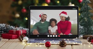 Happy family wearing santa hats on laptop video call, with christmas decorations and tree. christmas, festivity and communication technology digital composite video.