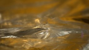 RACK FOCUSING two layers of foil with the top and bottom layersing up and down. DEFOCUSED textured colorful foil with yellow and gold coloring reflect with many contours and shapes. - Powered by Shutterstock - Get 15% off with code: PIKWIZARD15