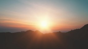 Mountain peak silhouette colorful sunrise. Bright sun rise up over mount range with blue orange clouds and sun rays. Beautiful highland wild landscape. Nature sunset background. Cinematic drone shot - Powered by Shutterstock - Get 15% off with code: PIKWIZARD15