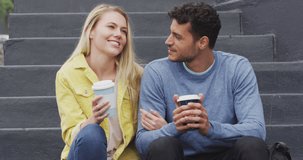 Animation of heart icons floating over happy caucasian couple talking and drinking takeaway coffee. social media and communication interface concept digitally generated video.