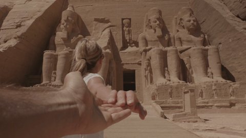 Follow me to concept: young woman holding hand of boyfriend leading the way to beautiful temple in Egypt - Personal perspective of girl giving hand to partner traveling together 