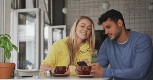 Animation of social media icons floating over happy caucasian couple using smartphone having coffee. social media and communication interface concept digitally generated video.