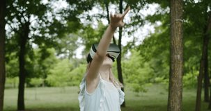 Little girl play with modern using virtual reality headset in park in blue dress