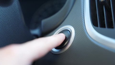 Car engine start button. Driver presses start-stop button in car. Close-up of driver hand starts engine. Driver hand on instrument panel of car. Electric start. 