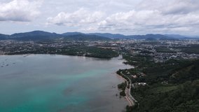 4K Aerial drone shot of Patong, Phuket Beach in Thailand with the blue Ocean with waves coming in and beach with nice houses on the background.