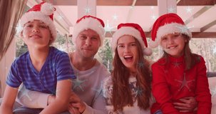 Animation of snow falling over smiling caucasian family with santa hats waving hands. christmas, winter, tradition and celebration concept digitally generated video.