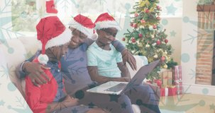 Animation of snow falling over smiling family with santa hats using laptop. christmas, winter, tradition and celebration concept digitally generated video.