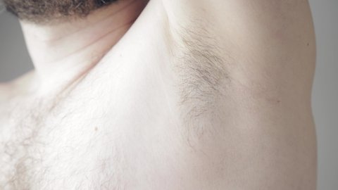 Close up slow motion shoot of man touching his hairy armpit before procedure of depilation or shaving. Removal of unwanted hair on body parts in cosmetology. Using of deodorant or antiperspirant from 