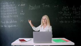 Female tutor teacher wearing glasses sitting explaining numbers on chalkboard having online virtual maths class with schoolchildren on video lesson using laptop computer. Distant education concept. - Powered by Shutterstock - Get 15% off with code: PIKWIZARD15