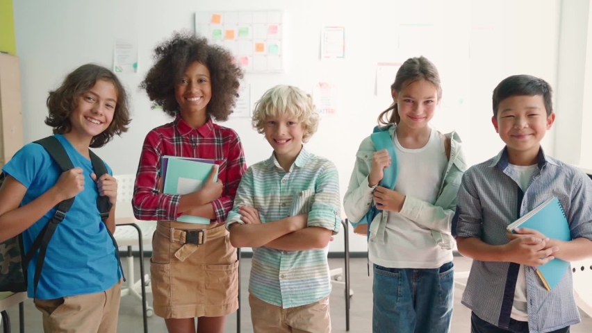 Portrait of cheerful smiling diverse multiethnic elementary school children standing posing in classroom looking at camera happy after school reopen. Diversity. Back to school concept. Royalty-Free Stock Footage #1079702546