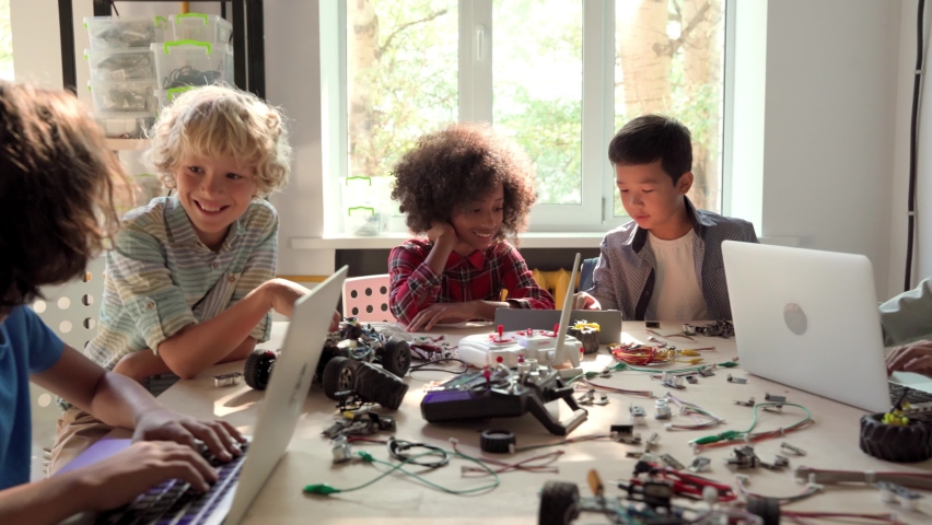 Group of multieracial schoolchildren interacting using gadgets laptops for programming at robotics engineering class. School science classroom of futuristic technologies. STEM education concept. Royalty-Free Stock Footage #1079702552