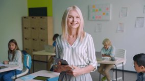 Smiling cheerful female teacher with group of diverse schoolchildren having maths class lesson holding tablet device gadget posing looking at camera in classroom. Education stem tech concept. - Powered by Shutterstock - Get 15% off with code: PIKWIZARD15