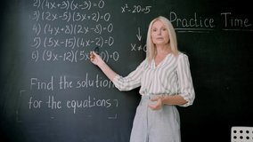 Webcam view of smiling tutor teacher talking having online virtual maths class with schoolchildren standing explaining showing formulas numbers on blackboard. Distant education concept. - Powered by Shutterstock - Get 15% off with code: PIKWIZARD15