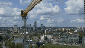 Ungraded: Tower construction crane stands motionless, swaying in the wind on background of aerial city view of Vilnius, Lithuania. Ungraded H.264 from camera without re-encoding.