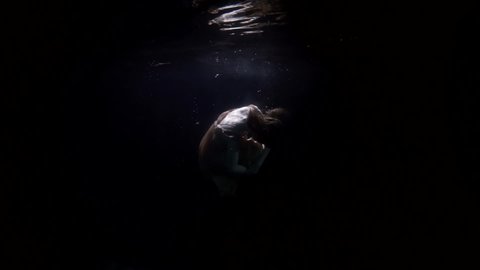 drowning woman in dark deepness, underwater shot, mystery and dramatic view