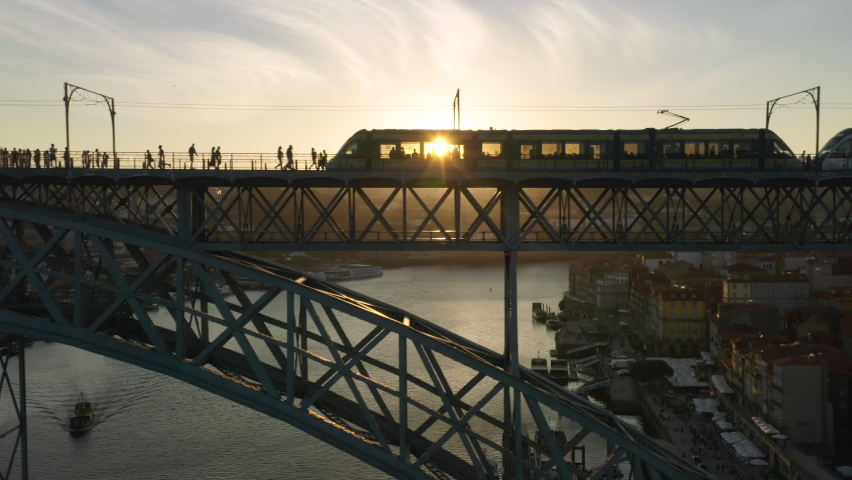 Porto. Portugal. Aerial footage of busy bridge stretching along banks of Douro River. Modern tram crossing picturesque route with golden sunset in the background. High quality 4k footage Royalty-Free Stock Footage #1079713088