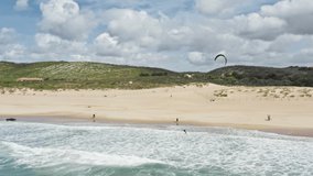 Birds eye view of man kitesurfing on beach of Atlantic ocean in Portugal, Europe. Overhead shot of sportsman practicing extreme water sport. Sporty guy enjoying training on kite, 4k footage