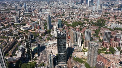 Backwards reveal of city. Aerial footage of skyscrapers in Elephant and Castle borough. Tall modern buildings towering above urban neighbourhood. London, UK