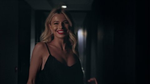 Stylish Blonde With Long Hair Runs In Hotel. She Is In An Evening Dress. She Smiles.