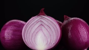 Purple Onions. Whole and slice purple onion on black background, rotate. 4K UHD video
