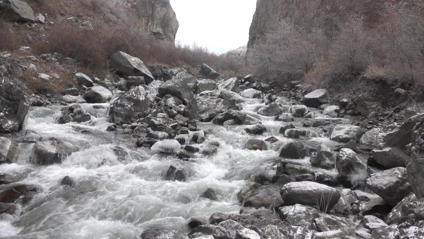 Cascade Creek flows through a mountain gorge. Winter in the mountains, rocks and trees are covered with ice and frost