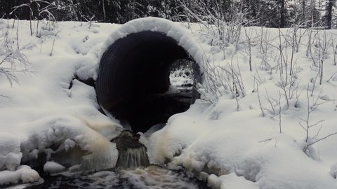 Winter road, winter culvert under iced, snow-covered thoroughfare, freezing of a watercourse. Road service task