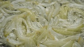 Frying sliced onion. Cooking onion on pan, close up. 4K UHD video 