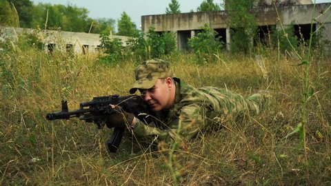 soldier in camouflage take aim with a rifle in a prone position
