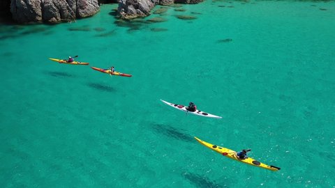 Aerial drone video of women team of sport kayak in iconic beach and small cove of Tsigrado, Milos island, Cyclades, Greece
