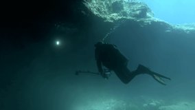 Scuba diver photographer swims in the cave. Cave diving in Mediterranean Sea, Cyprus
