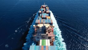 Aerial drone video above huge colourful container carrier vessel cruising deep blue open ocean sea