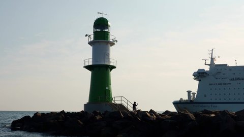 Rostock, Germany - Juli 12, 2020: lighthouse in Warnemuende Rostock with leaving ferry TT-Line